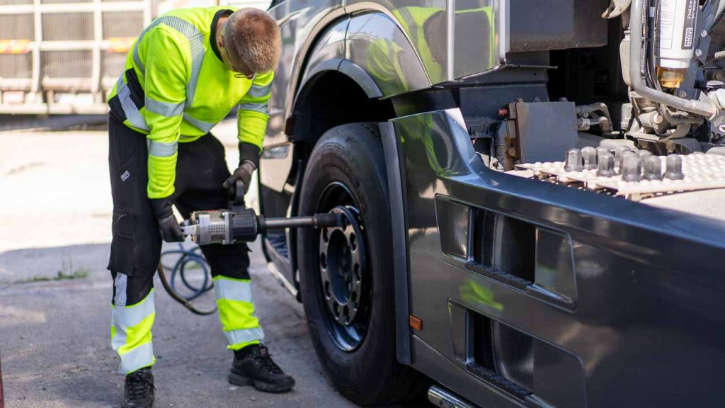 Pracownik mobilnej wulkanizacji dokręca koło ciężarówki kluczem udarowym na pneumatyce